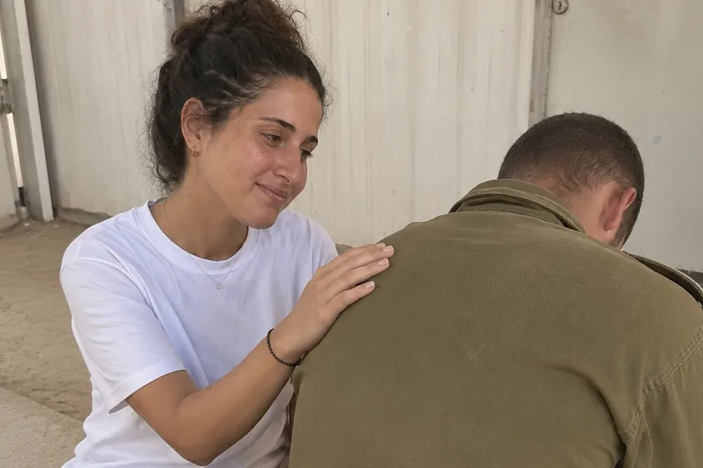 מתנדבת יושבת עם לוחם מילואים, ידה על כתפו